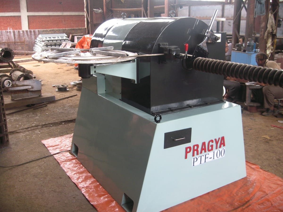 PRAGYA PTF-100 fin tube machine winding fin strip onto a tube, the finned length emerging from the head